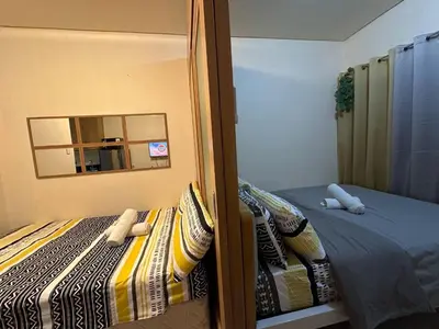 a small bedroom with a bed and a mirror at Macc staycation in Manila