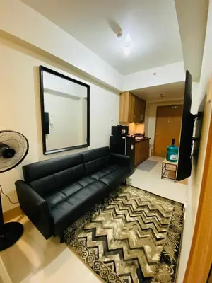 a living room with a black leather couch and a rug at SMDC Shore 3 Residences in Manila