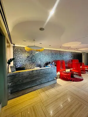 a lobby with red chairs and a wall with a mural at Amira Luxury at Novotel Suites Manila near Makati and BGC in Manila