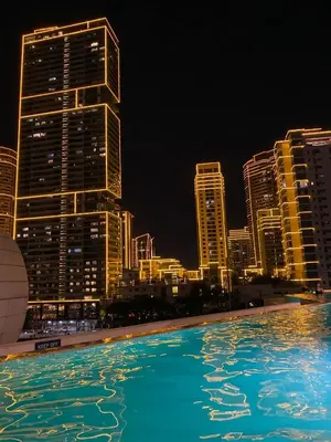 a swimming pool with a city skyline at night at Amira Luxury at Novotel Suites Manila near Makati and BGC in Manila