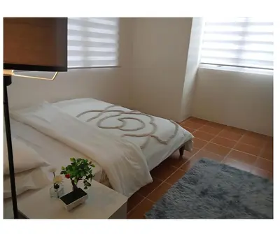 a bedroom with a bed and a table with a plant at 2BR Pioneer Woodland connected to Metro Rail Station SM Light,BONI Mandaluyong, Metro Manila,Philippines in Manila