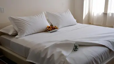 a white bed with a bowl of flowers on it at 1BR Covent Garden South Tower University Belt- SM Sta Mesa, Metro Manila,Philippines in Manila