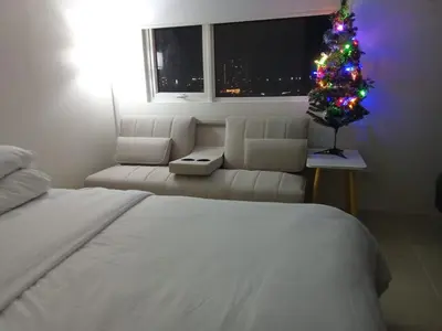 a bedroom with a christmas tree and a couch at 1BR Covent Garden South Tower University Belt- SM Sta Mesa, Metro Manila,Philippines in Manila