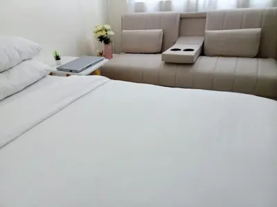 a bedroom with a white bed and a couch at 1BR Covent Garden South Tower University Belt- SM Sta Mesa, Metro Manila,Philippines in Manila