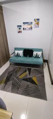 a blue couch sitting in a room with a rug at Reden Staycation in Manila
