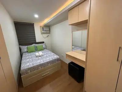 a small bedroom with a bed and a desk at Away from but close like family room in Manila