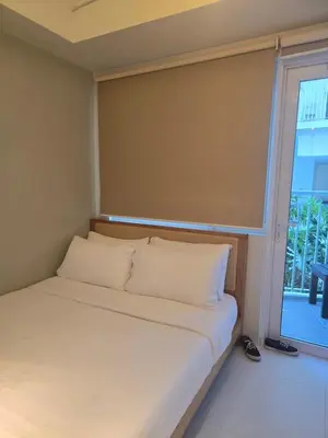 a bed with white pillows in a room with a window at Jazz Residence- Makati in Manila