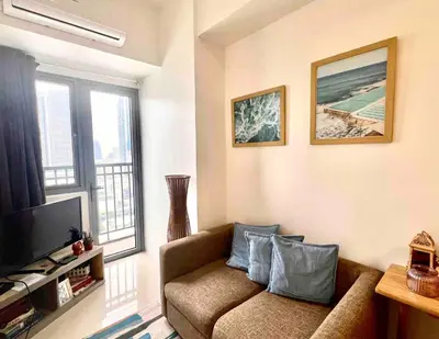 a living room with a couch and a television at Condo Ortigas CBD in Manila