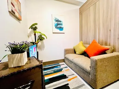 a living room with a couch and colorful pillows at Central Ortigas Center Condo in Manila