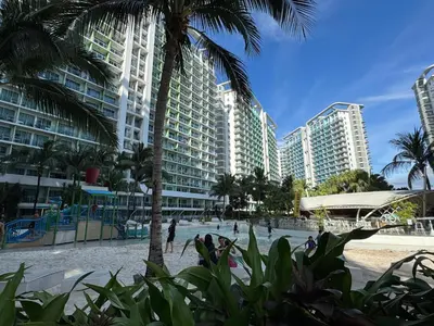 a beach with tall buildings and a palm tree at Azure Staycation Condo Unit in Manila