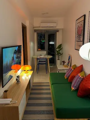 a living room with a green couch and a table at Cozy Mid-Century Condo with a Skyline View in Manila