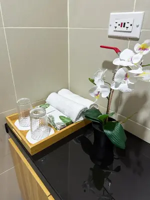 a table with a clock and a vase with flowers on it at Cozy Mid-Century Condo with a Skyline View in Manila