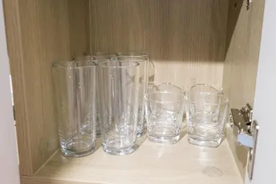 a group of empty glasses sitting on a shelf at Luxe 1BR with WiFi, Karaoke and Balcony Near SM Megamall in Manila