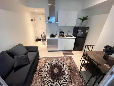 a living room with a couch and a kitchen at Staycation in Azure Paranaque in Manila