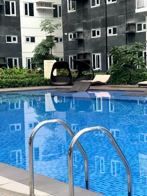 a swimming pool with two chairs in front of a building at FRIENDS TV Staycation in Manila