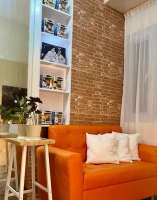 an orange couch in a room with a brick wall at FRIENDS TV Staycation in Manila