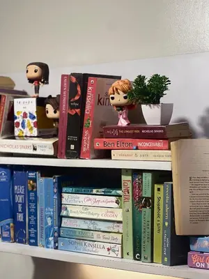 a book shelf filled with books with dolls and a plant at FRIENDS TV Staycation in Manila
