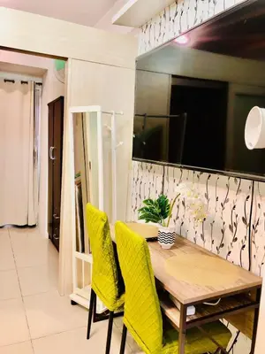 a dining room with a wooden table and yellow chairs at JAZZ RESIDENCES- Amaya Stays in Manila