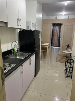 a kitchen with a sink and a black refrigerator at JAZZ RESIDENCES- Amaya Stays in Manila