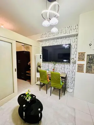 a living room with a table and chairs and a tv at JAZZ RESIDENCES- Amaya Stays in Manila