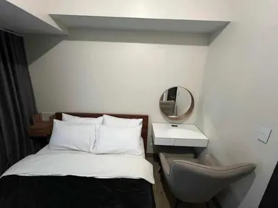 a small bedroom with a bed and a mirror at Holiday suite at Park Mckinley West in Manila