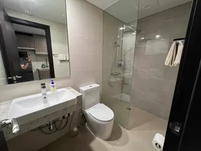 a bathroom with a toilet and a sink and a shower at Holiday suite at Park Mckinley West in Manila