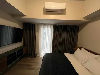a hotel room with a bed and a television at Holiday suite at Park Mckinley West in Manila
