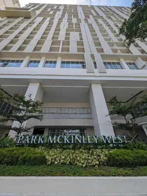 a tall white building with a sign in front of it at Holiday suite at Park Mckinley West in Manila