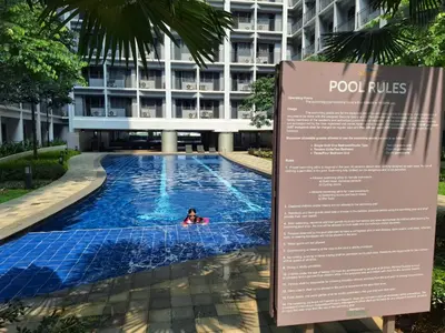 a person swimming in a pool in front of a building at Velvet Room near MOA with a Cozy, Comfy Bed in Manila