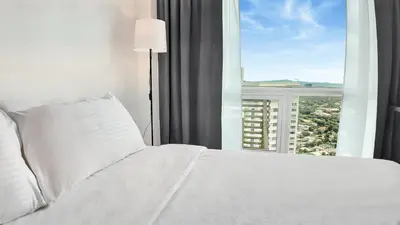 a bedroom with a white bed and a large window at Sky Suite Makati Modern Penthouse near Greenbelt in Manila