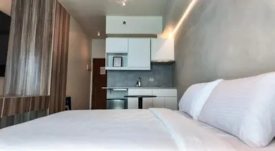 a bedroom with a white bed and a small kitchen at Sky Suite Makati Modern Penthouse near Greenbelt in Manila