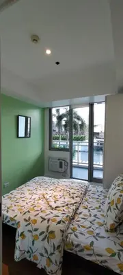 a bedroom with a bed with a comforter and windows at Azure Family Room Condo Unit in Manila