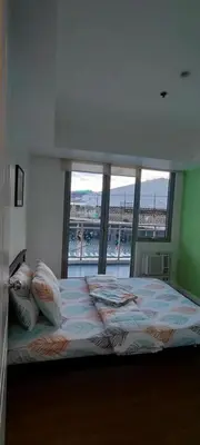 a bedroom with a bed with a large window at Azure Family Room Condo Unit in Manila