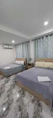 two beds in a bedroom with blue curtains at Family Unit at Mary's Staycation in Tanza Cavite Condo Type good for 4 person in Tanza
