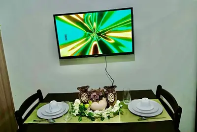 a dining room table with a television on the wall at La Chicka staycation in Manila