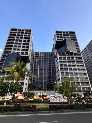 two tall buildings with palm trees in front of a street at La Chicka staycation in Manila