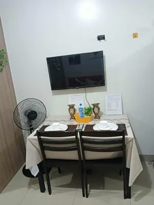 a table with two chairs and a television on a wall at La Chicka staycation in Manila