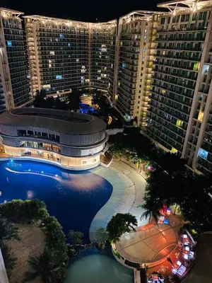 a view of a large building with a swimming pool at night at Uno Tahanan Azure in Manila