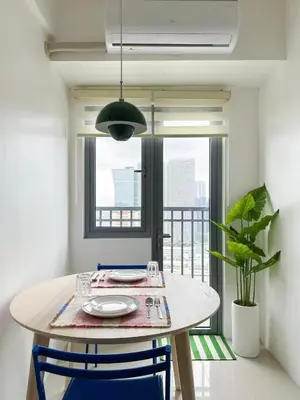 a dining room table with two chairs and a window at Cozy Mid-Century Condo with a Skyline View in Manila