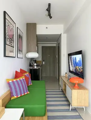 a living room with a green couch and a flat screen tv at Cozy Mid-Century Condo with a Skyline View in Manila