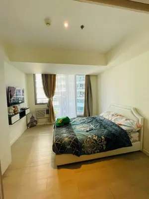 a bedroom with a bed and a large window at Staycation in Azure Paranaque in Manila