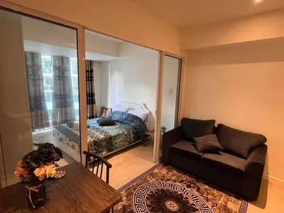 a living room with a couch and a bed at Staycation in Azure Paranaque in Manila