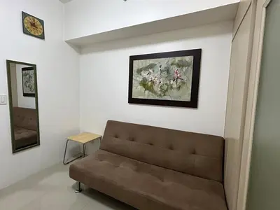 a living room with a couch and a painting on the wall at 1-Br Unit at Light Residences in Manila