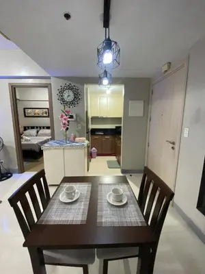 a dining room with a table and chairs and a kitchen at JNL Condotel in Manila