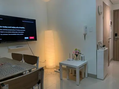a living room with a table and a tv on the wall at Tropical Sanctuary in Pasay City in Manila