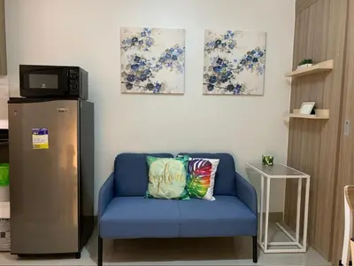 a blue couch with a pillow in a room with a refrigerator at Tropical Sanctuary in Pasay City in Manila