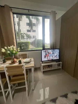 a living room with a table and a tv and a window at StayWise Space Manila in Manila