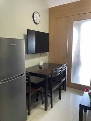 a kitchen with a table and a refrigerator and a clock at Shell Residences in Manila