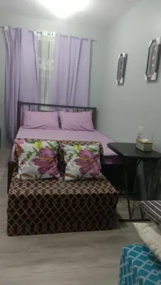a bed with pink pillows and a bench with a table at Josephine Macatula in Santa Rosa