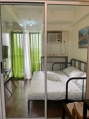 two beds in a bedroom with green curtains at Satori Residences in Manila